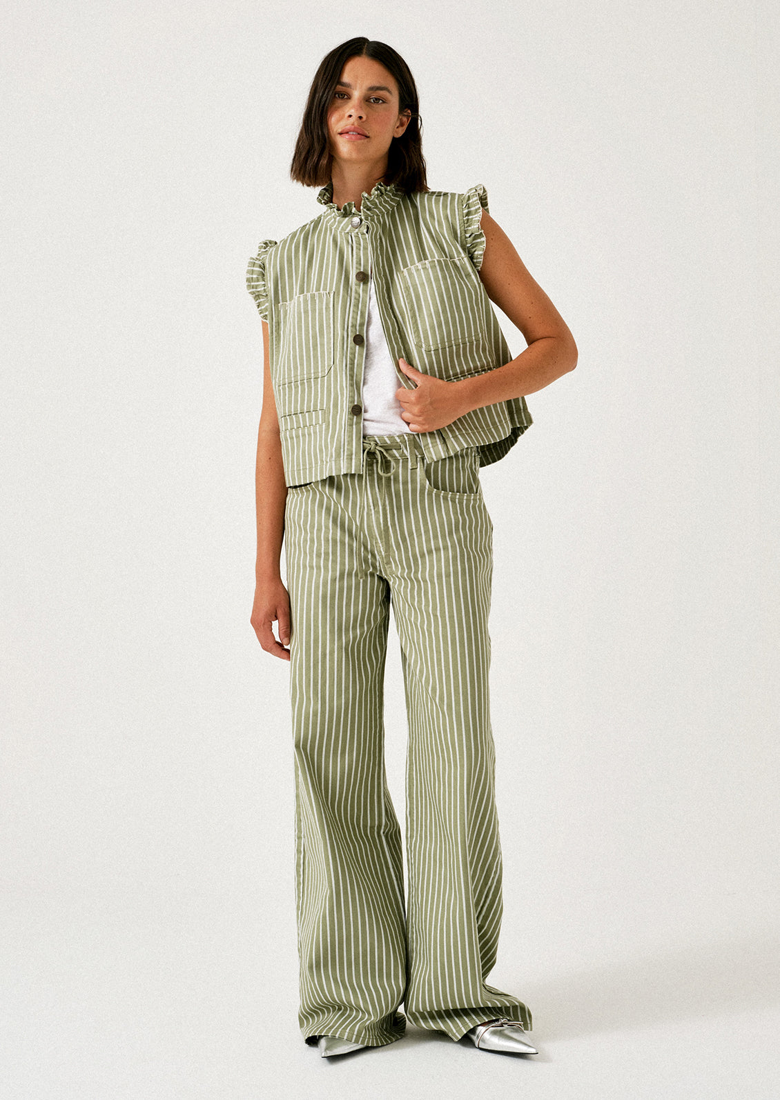 A woman wearing a pair of green jeans with white stripes and drawstring waist.