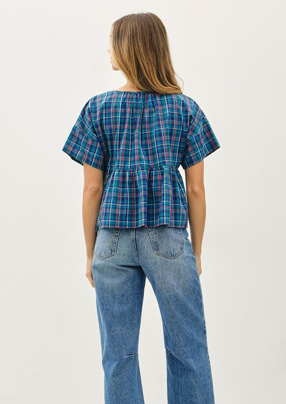 Person wearing a blue plaid shirt and jeans on a white background