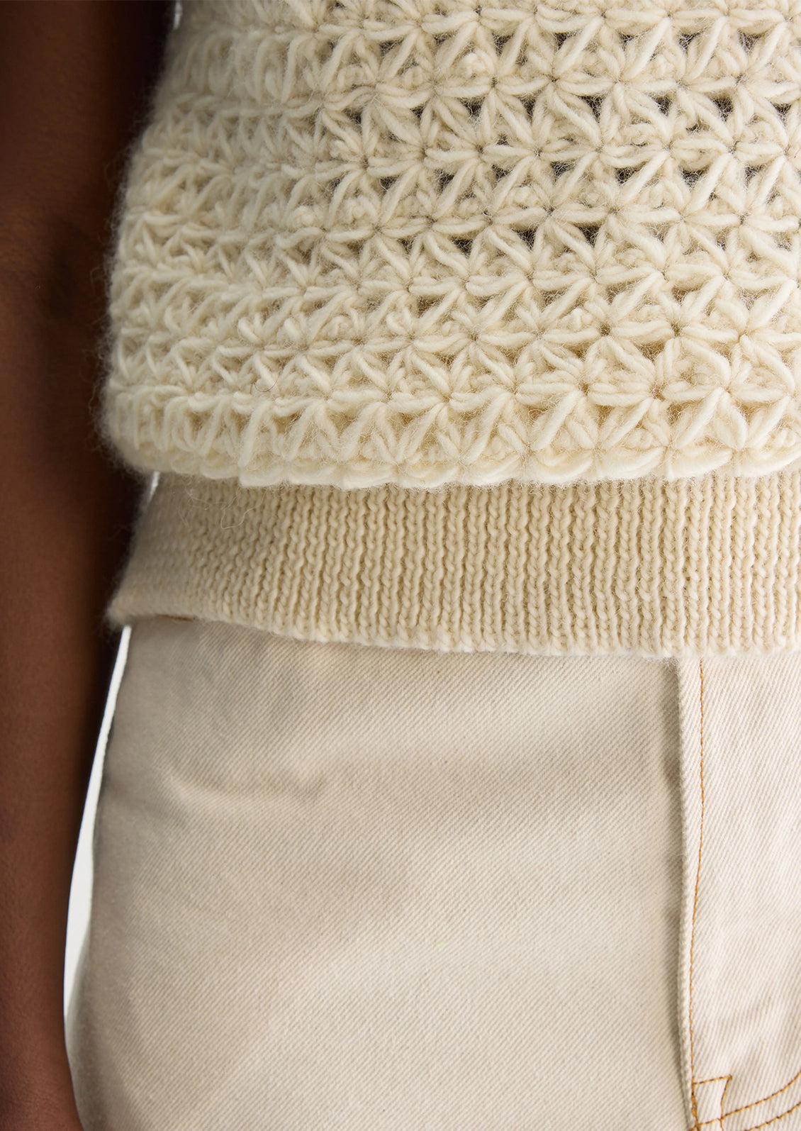 A woman wearing a sleeveless crewneck sweater vest in triangular open weave wool.