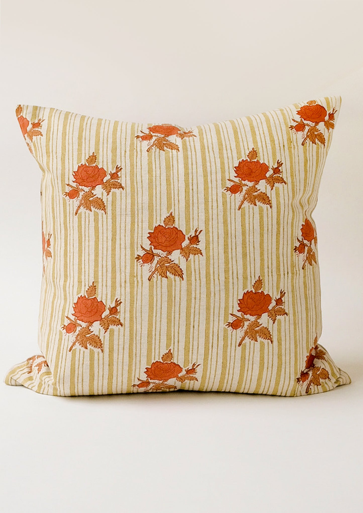 A pillow with green vertical stripes and orange floral pattern.