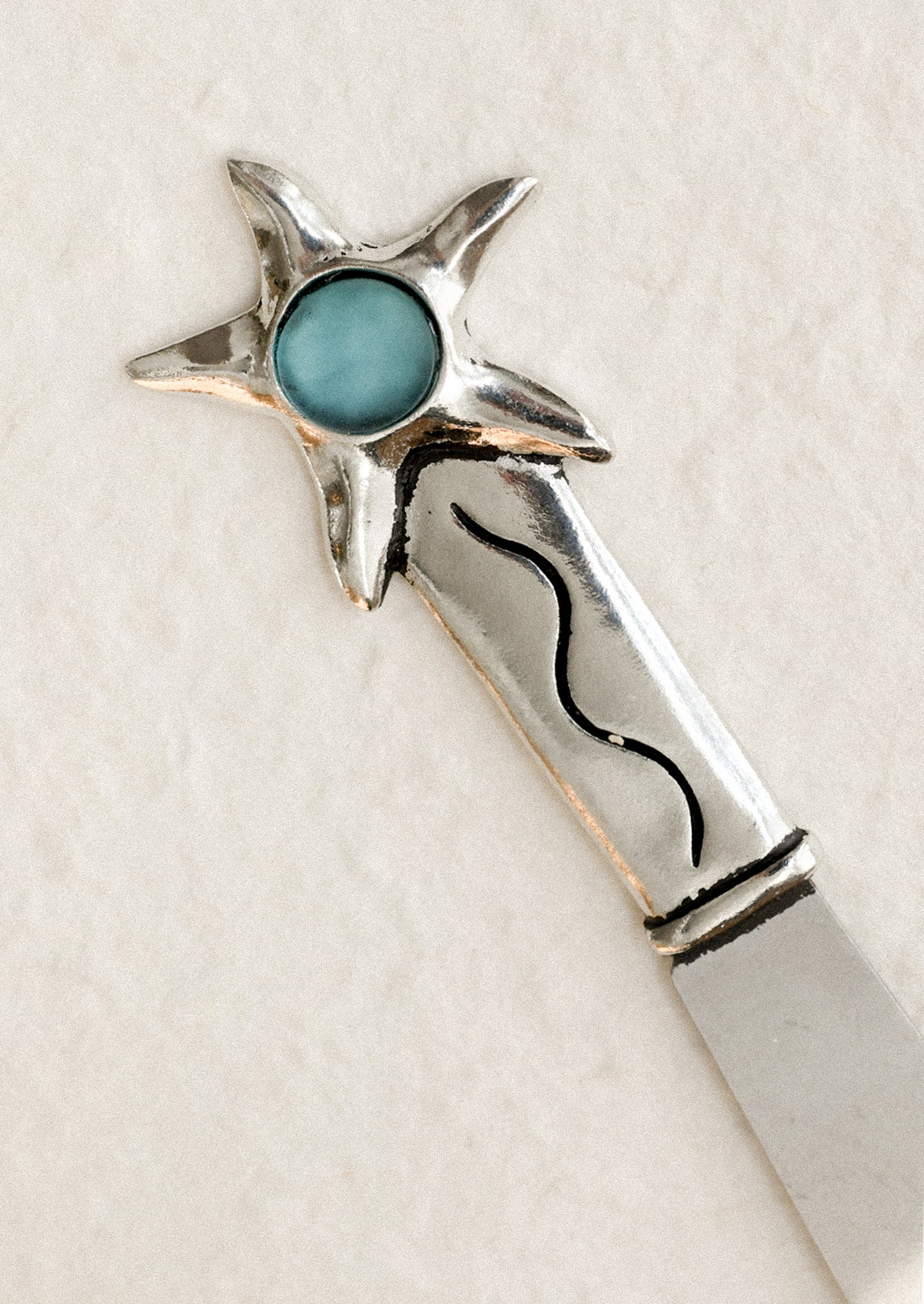 Silver butter knife with turquoise stone on a white background