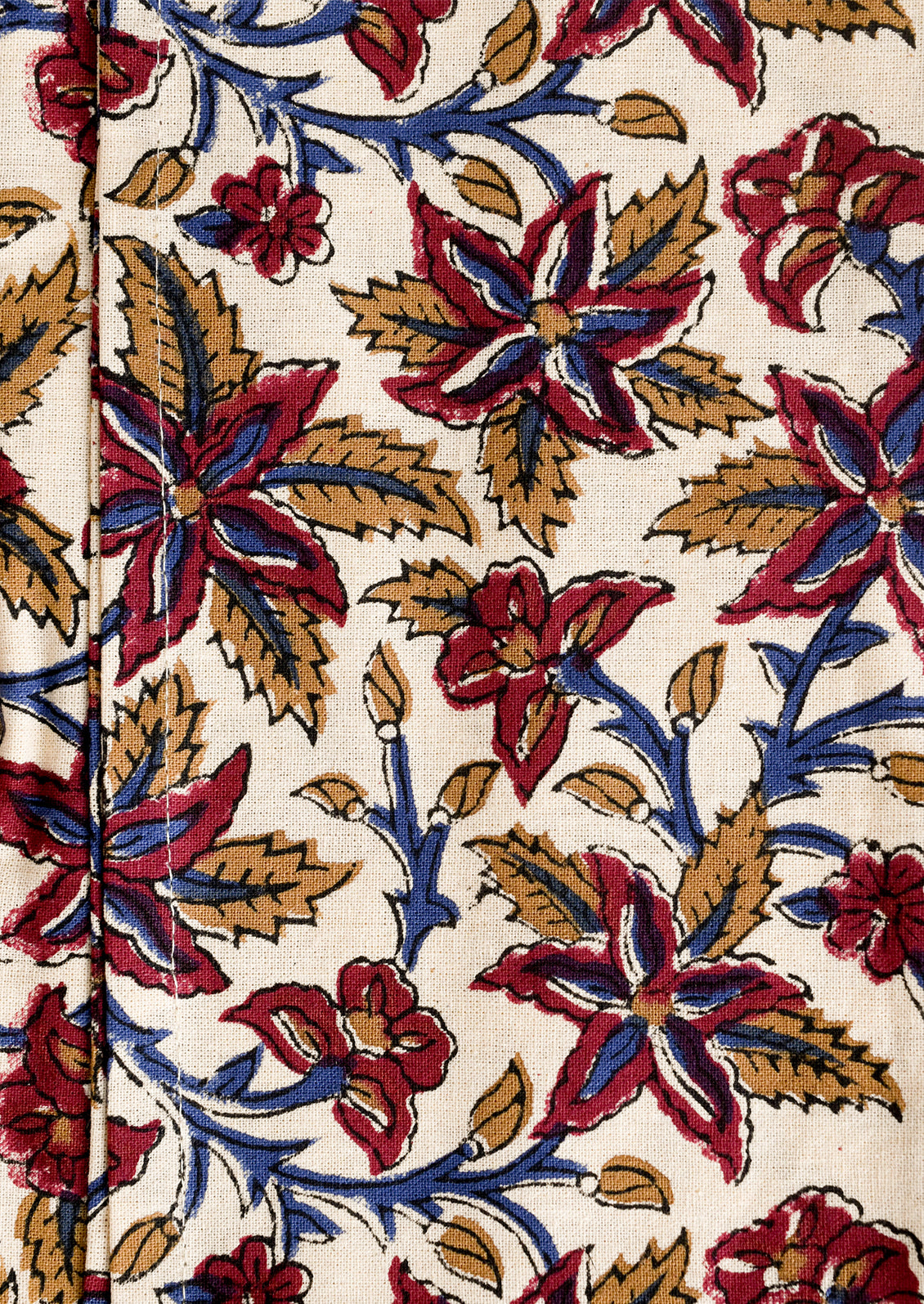 Close-up of a fabric with a floral pattern featuring red, blue, and gold colors on a beige background.