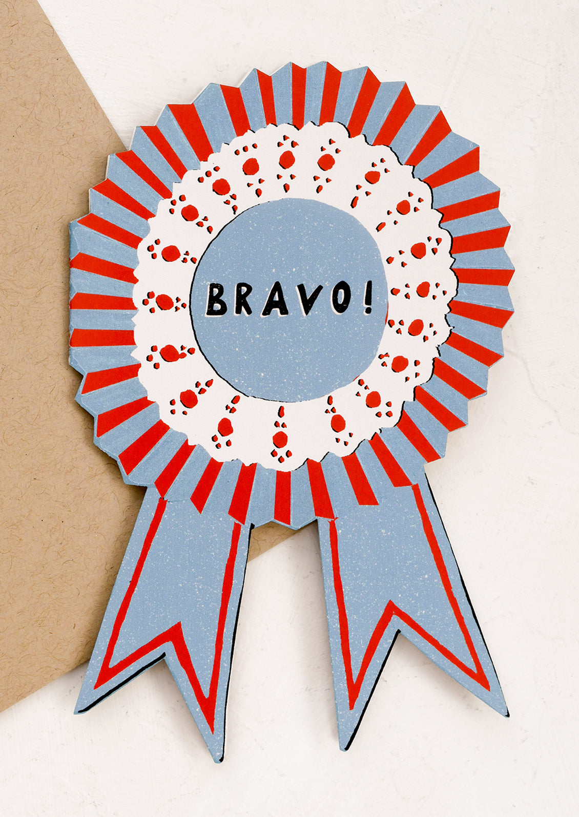 A diecut greeting card in the shape of an award ribbon.