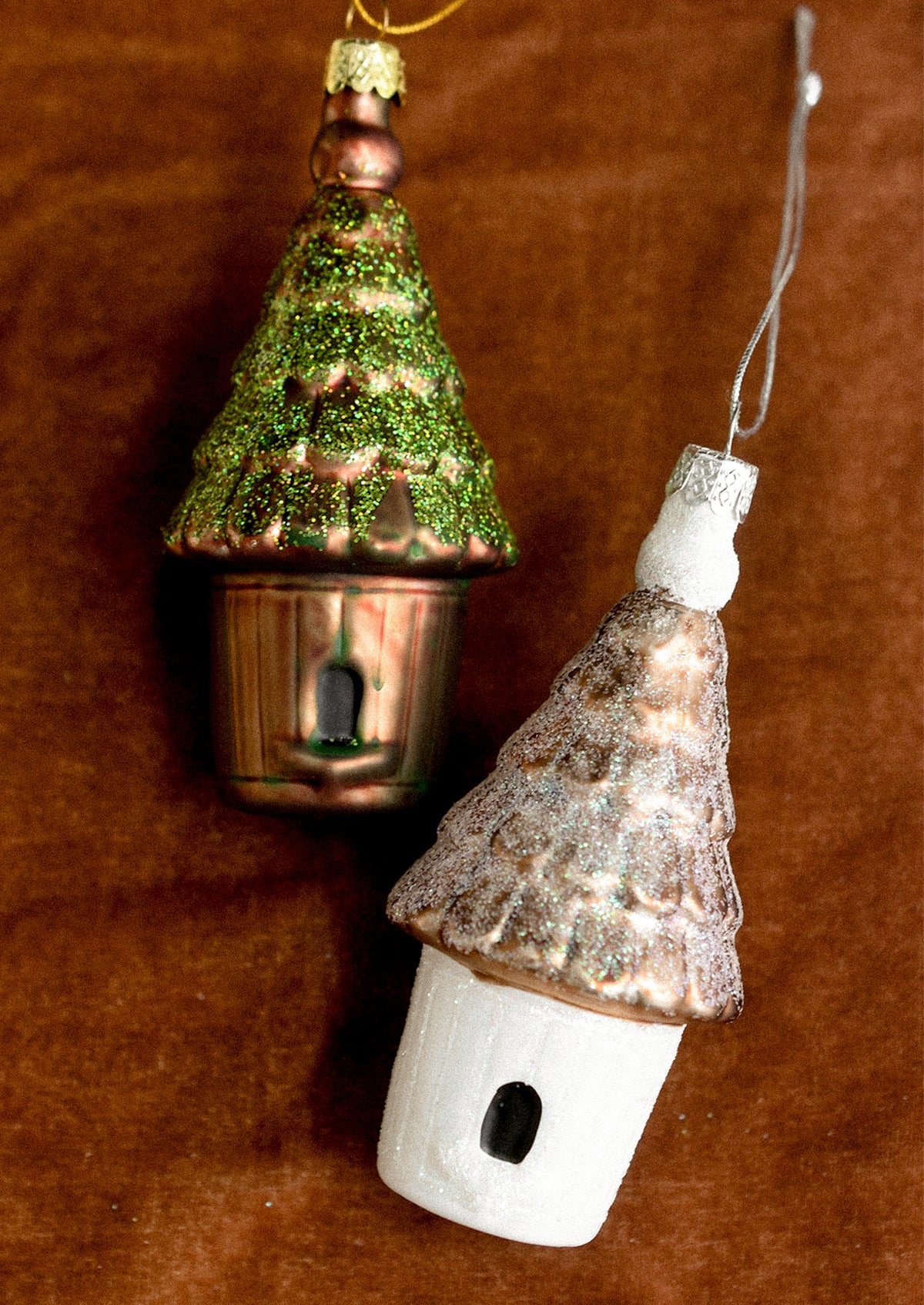 Glass ornaments depicting birdhouses, in white and brown color options.