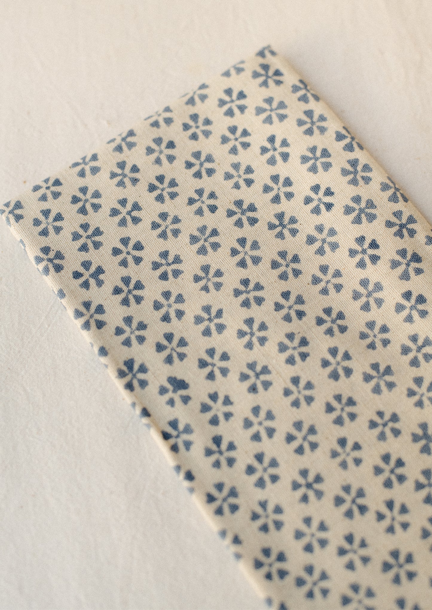 A pair of natural cotton-linen napkins with blue repeating floral pattern.
