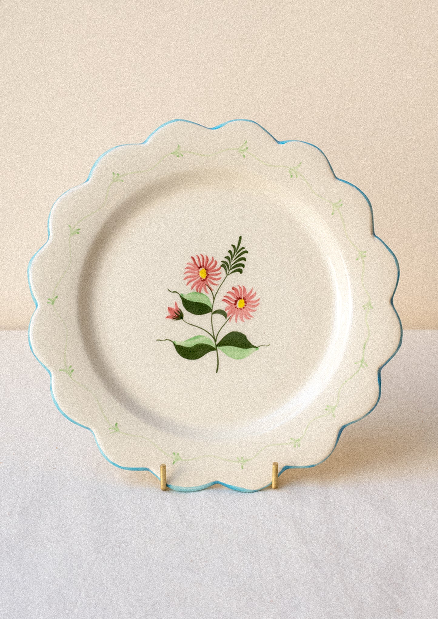 Decorative ceramic plate with pink floral design and blue scalloped edge.