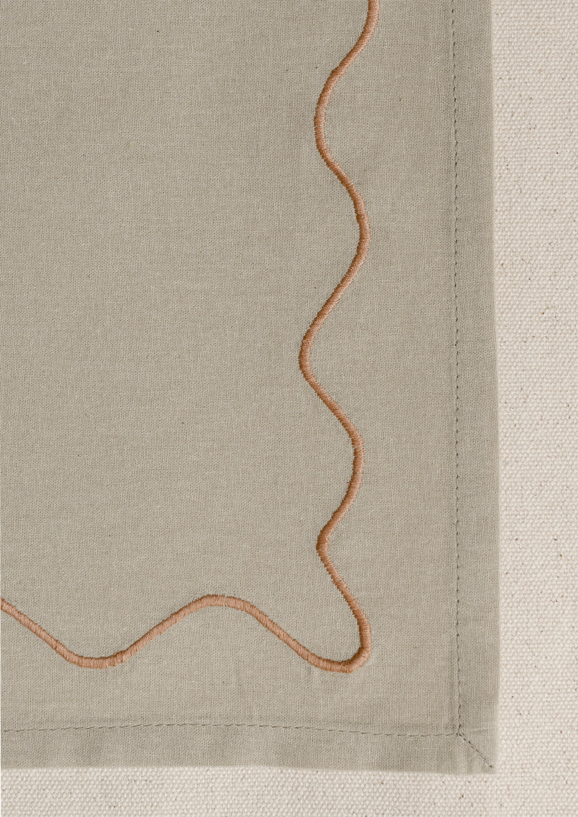 A tan placemat with peach squiggle border.