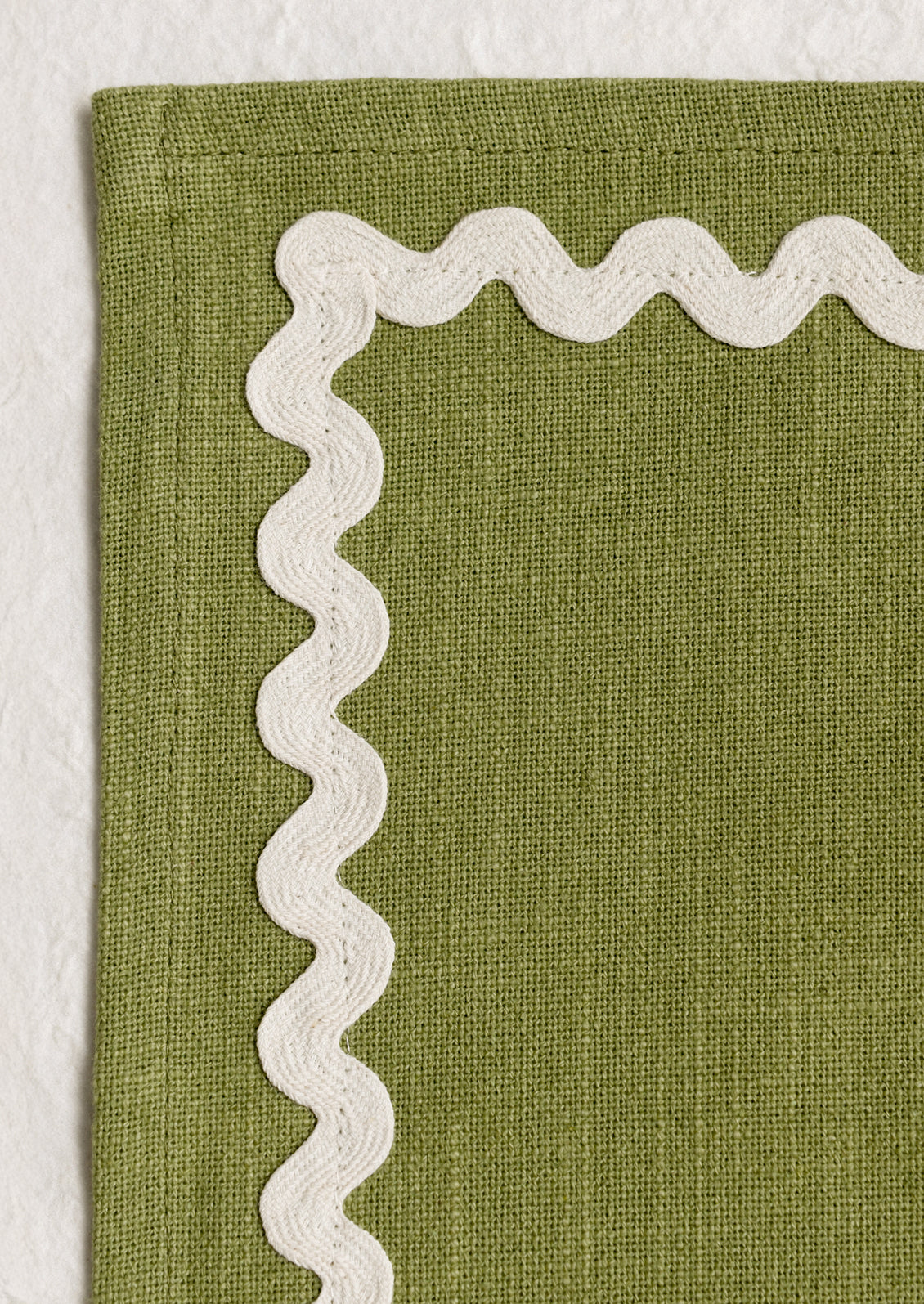 A moss green placemat with white ricrac trim border.