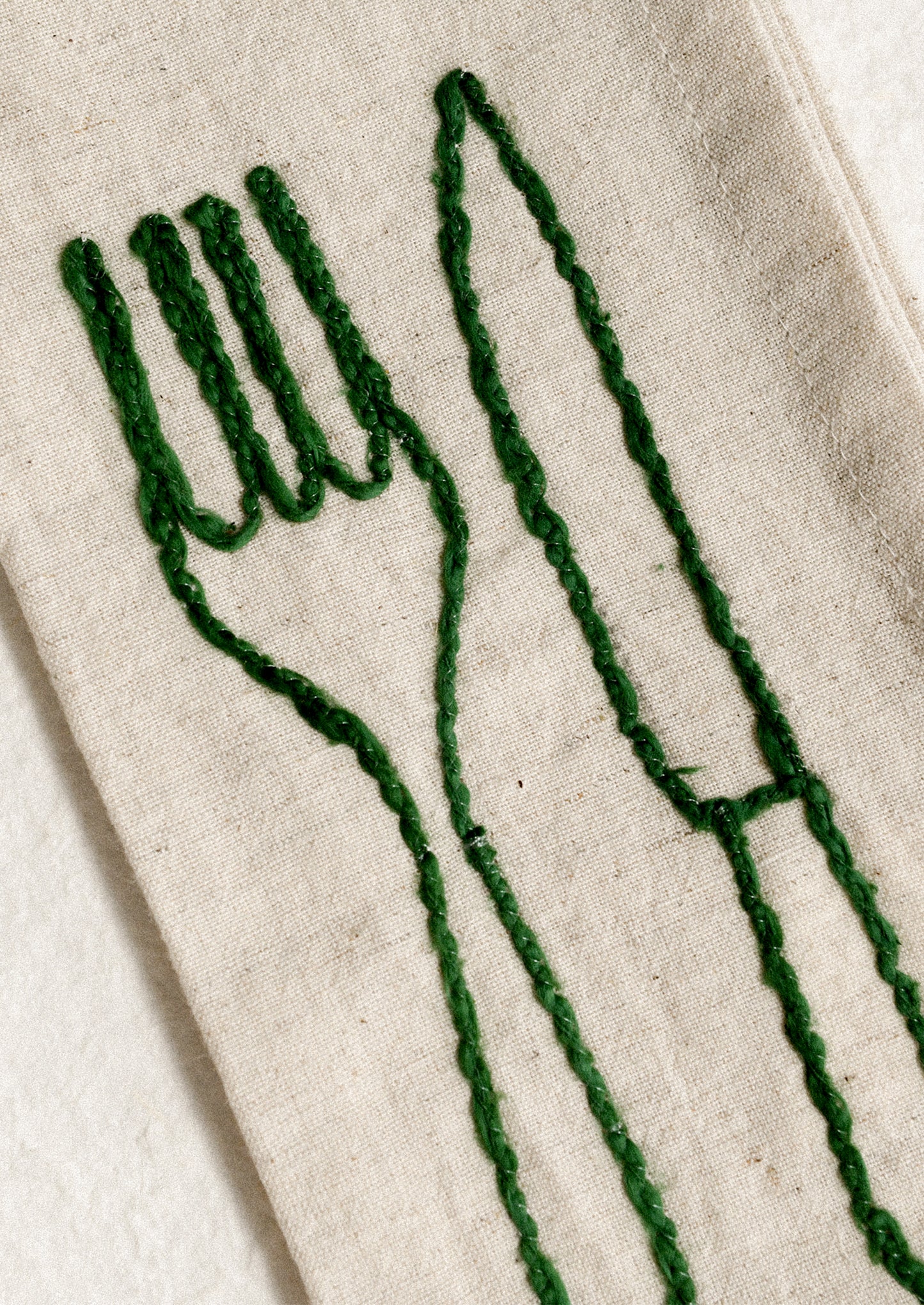 A set of natural linen napkins with embroidered fork and knife motif in assorted colors.
