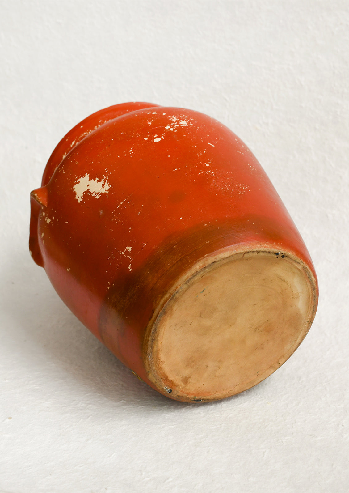 An antique cookie jar in red with chippy floral painted design.