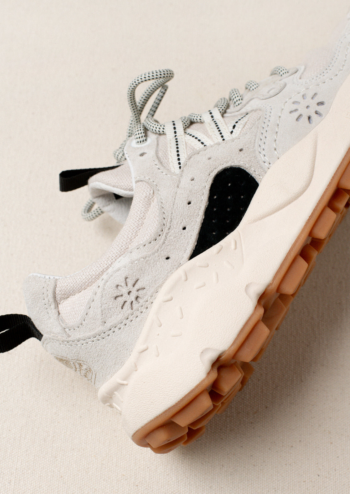 A pair of sporty sneakers in neutral colors with flower cutout detailing.