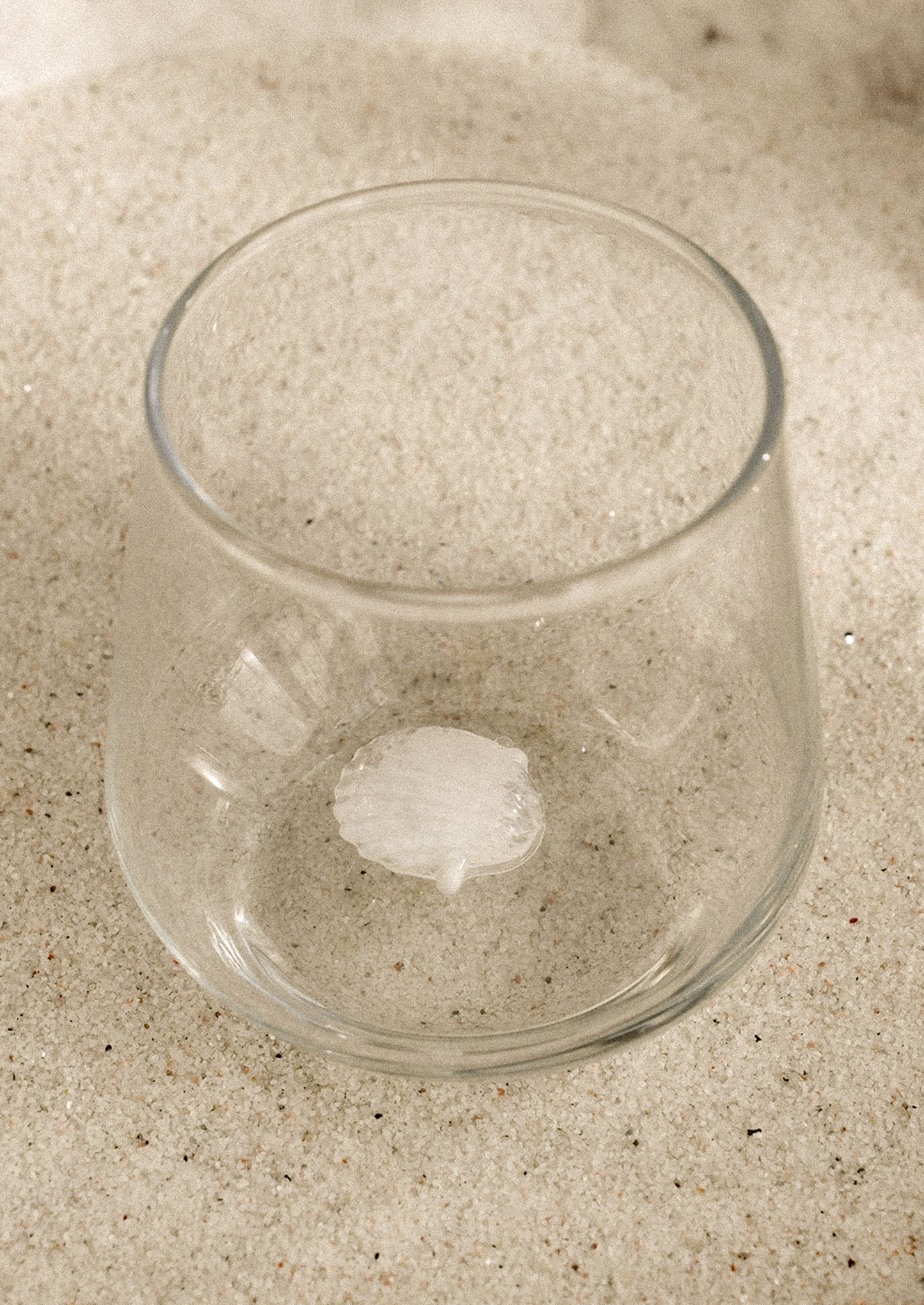 A clear stemless glass with three-dimensional shell detail at bottom of glass.