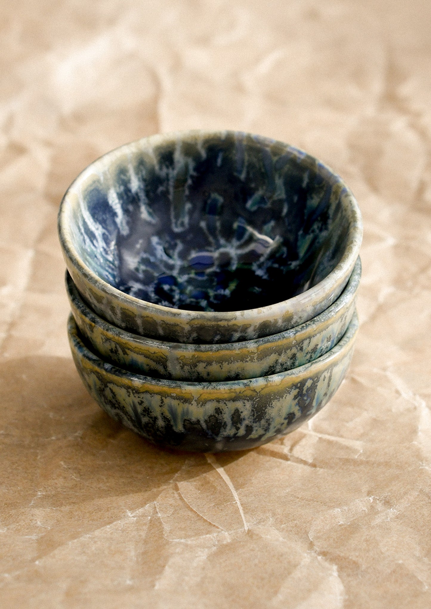 Stack of blue ceramic bowls on a textured beige surface