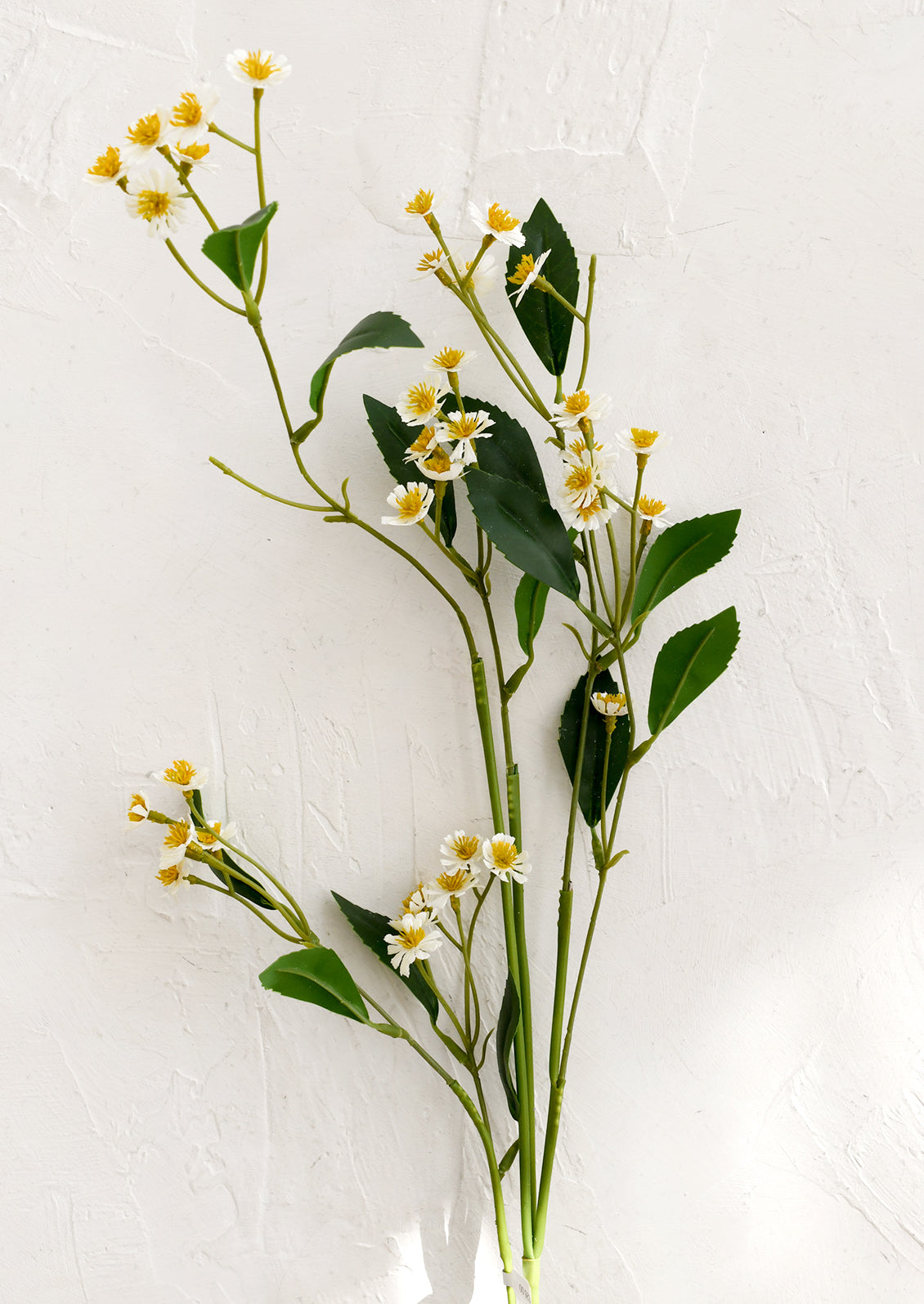 Artificial plant with green leaves and small yellow flowers on a white background