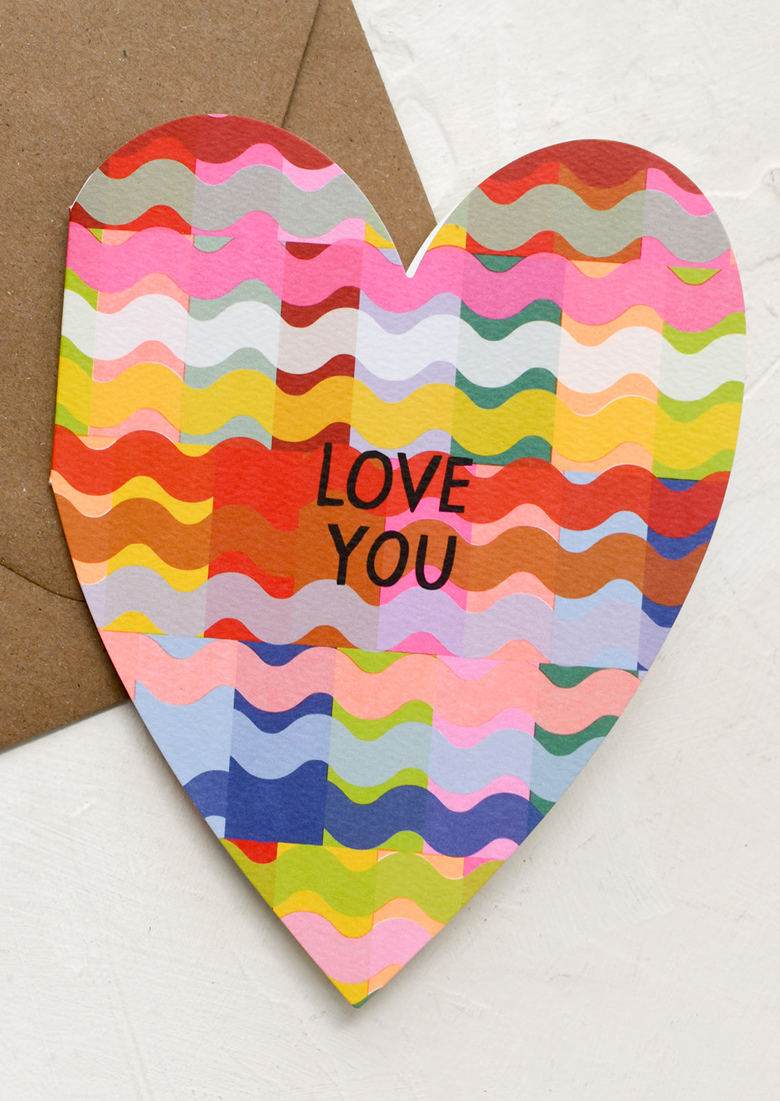 A heart shaped greeting card in bright color pattern reading "LOVE YOU".