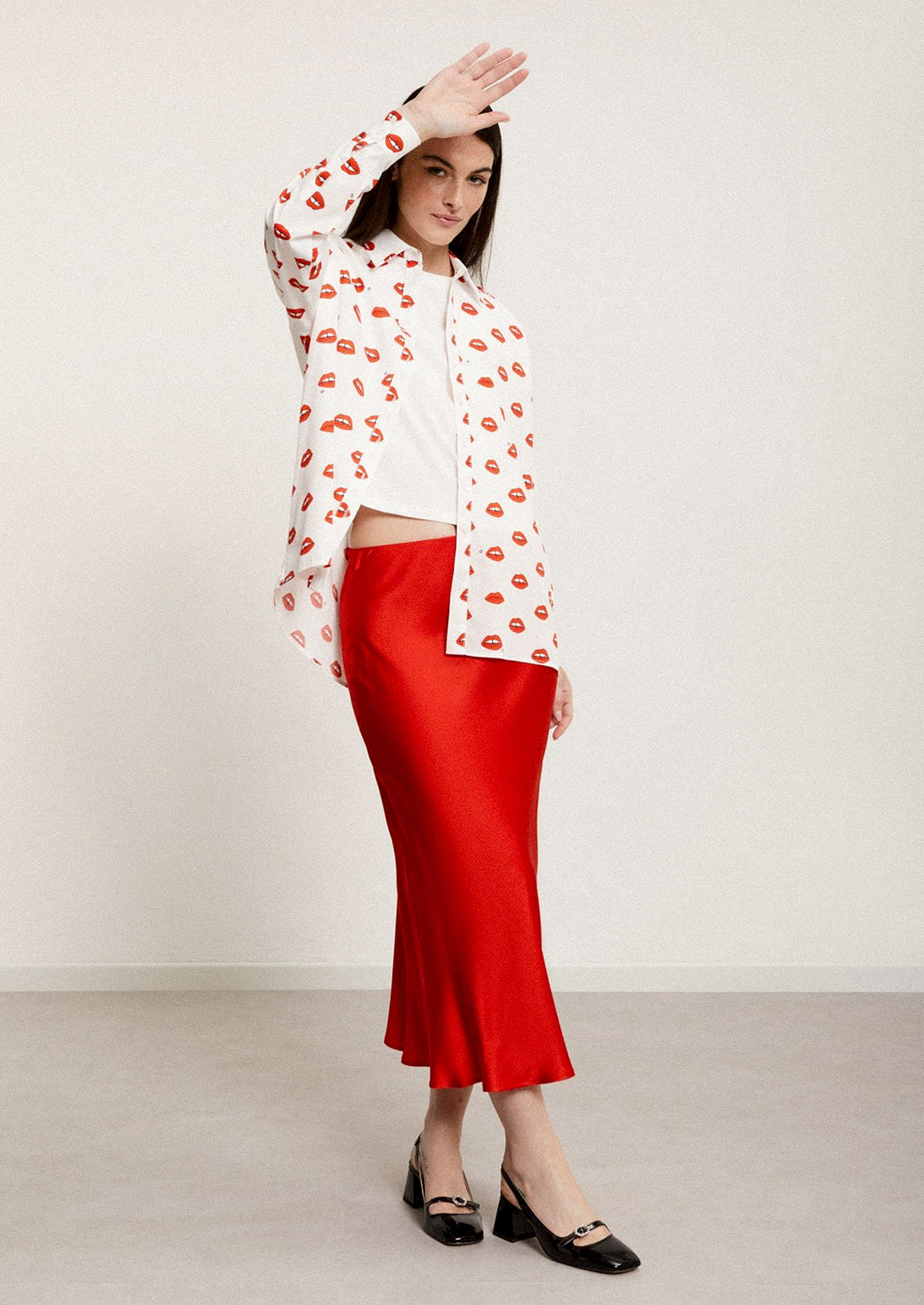 A woman wearing a red flowy sateen skirt.