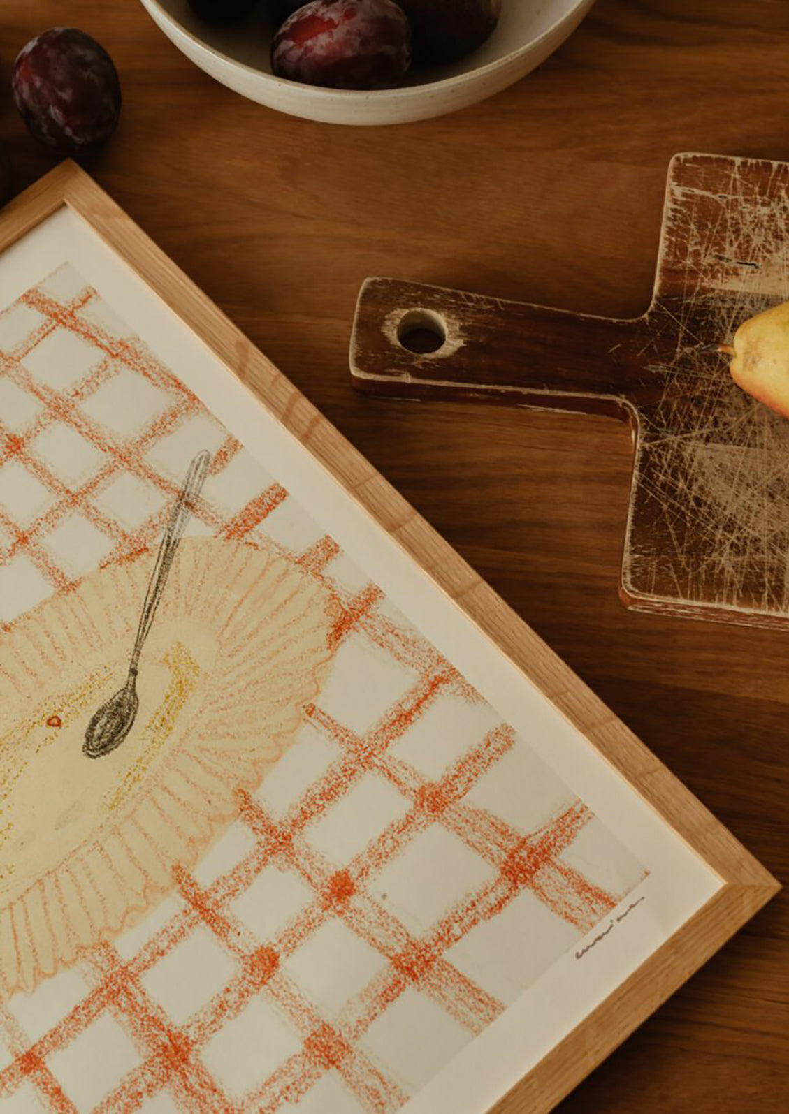 An art print of a drawing of a yellow plate on an orange and white checkered surface.