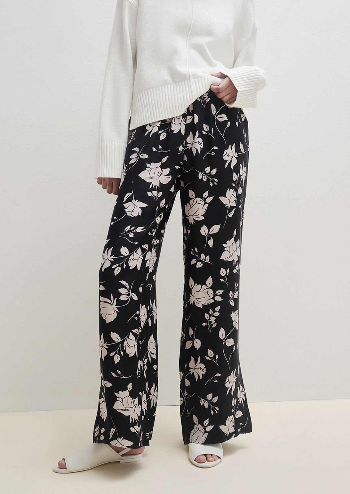 A person wearing a pair of monochrome floral pants in black and white.