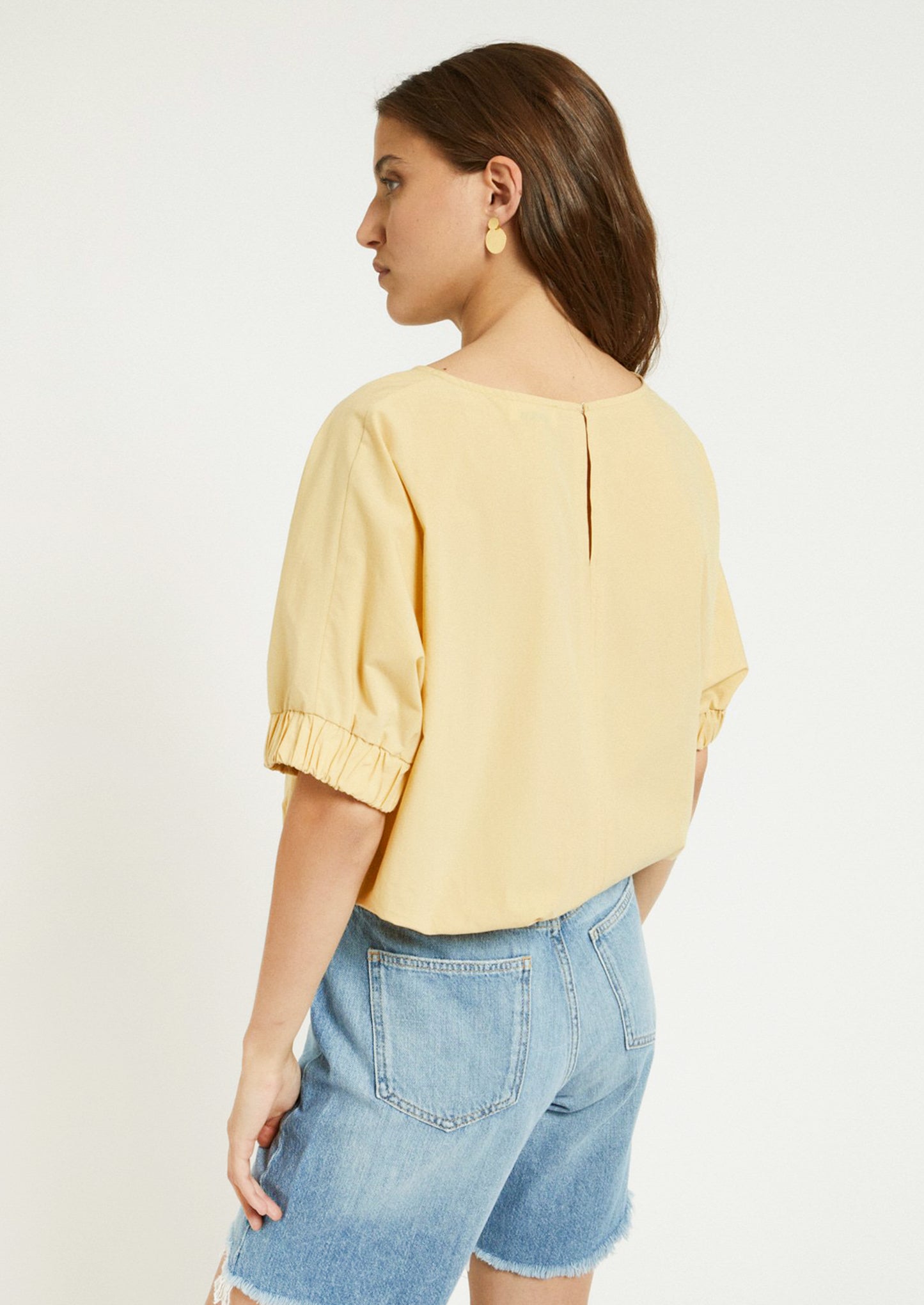 A woman wearing a short sleeve blouse in yellow color.