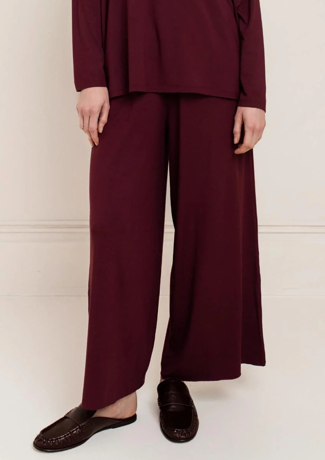 A person wearing a pair of burgundy wide leg pants.
