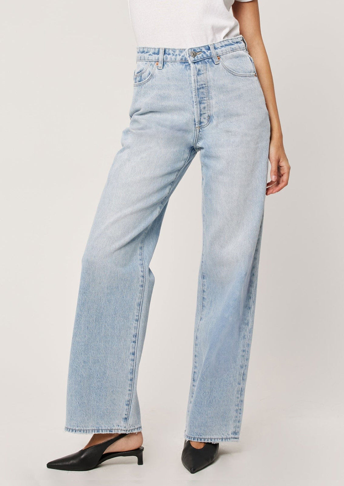 A person wearing a pair of straight leg relaxed jeans in light blue denim.