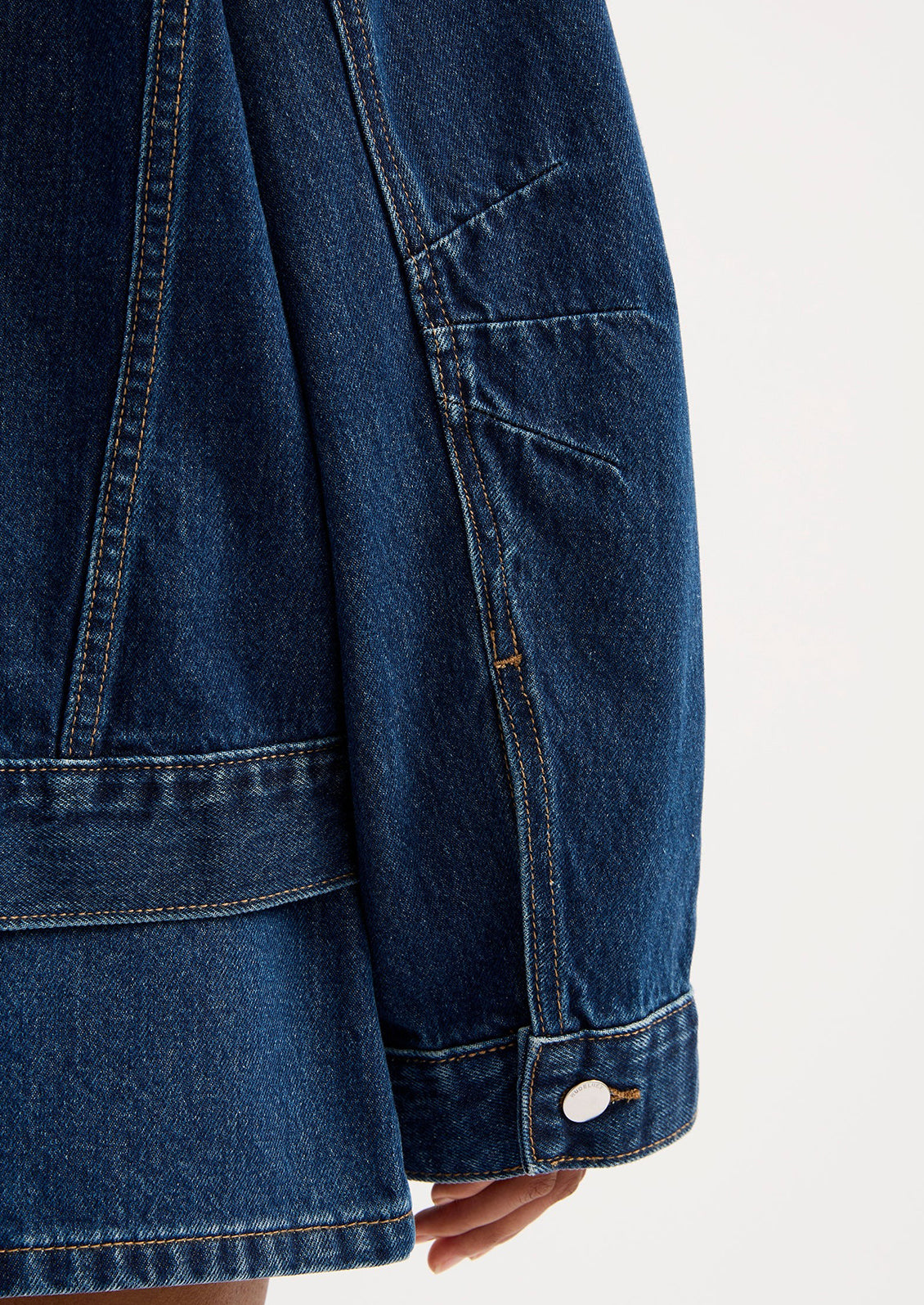 A woman wearing an oversized denim jacket in dark wash.