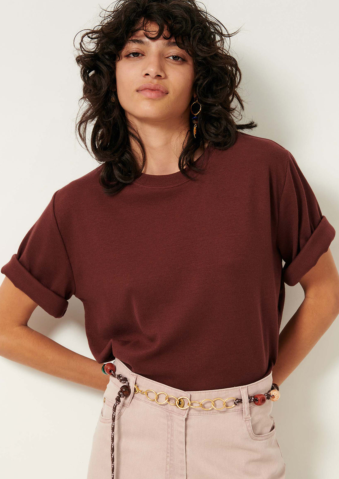 A woman wearing a short sleeve t-shirt with cuffs rolled up.