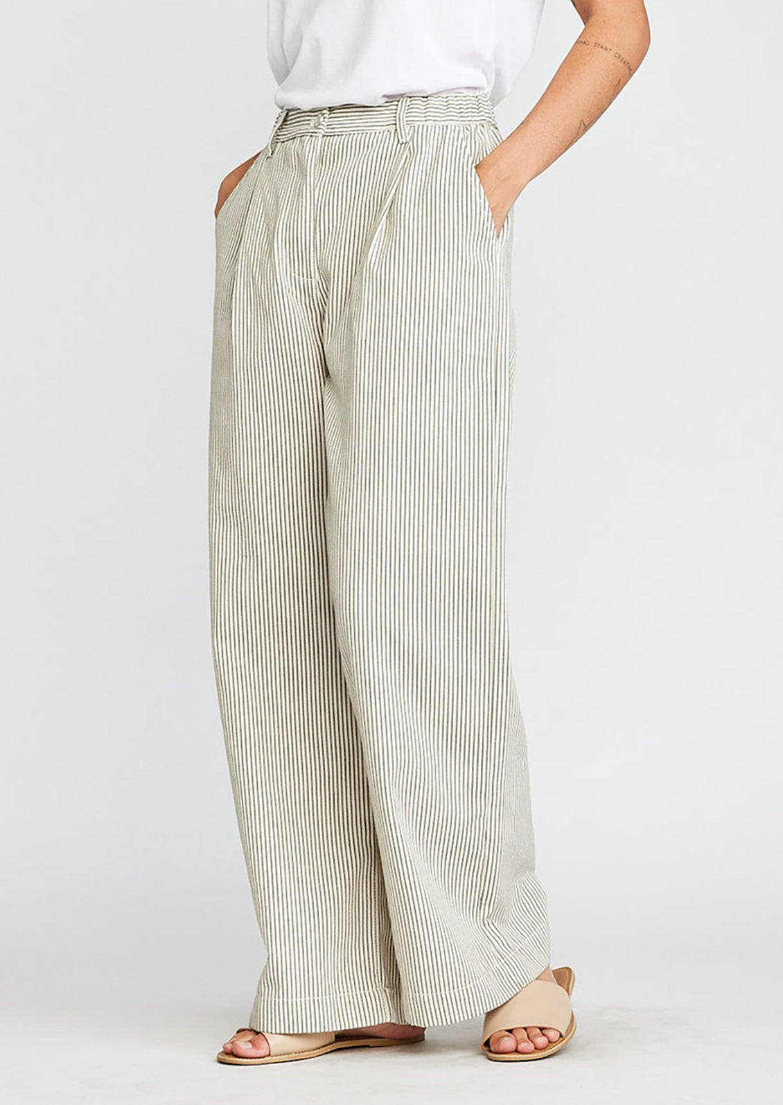 A woman wearing a pair of wide leg pleat front pants in green pinstripe.