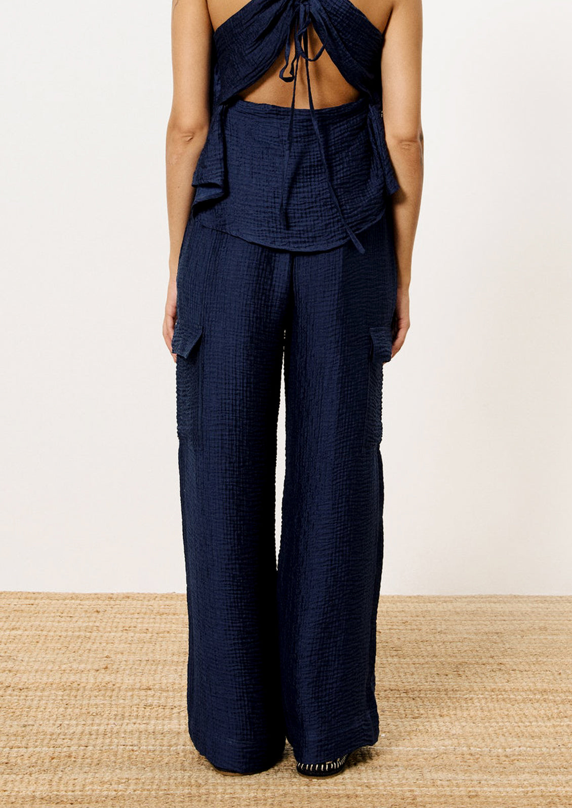 A person wearing a pair of navy blue crinkle texture cargo pants.