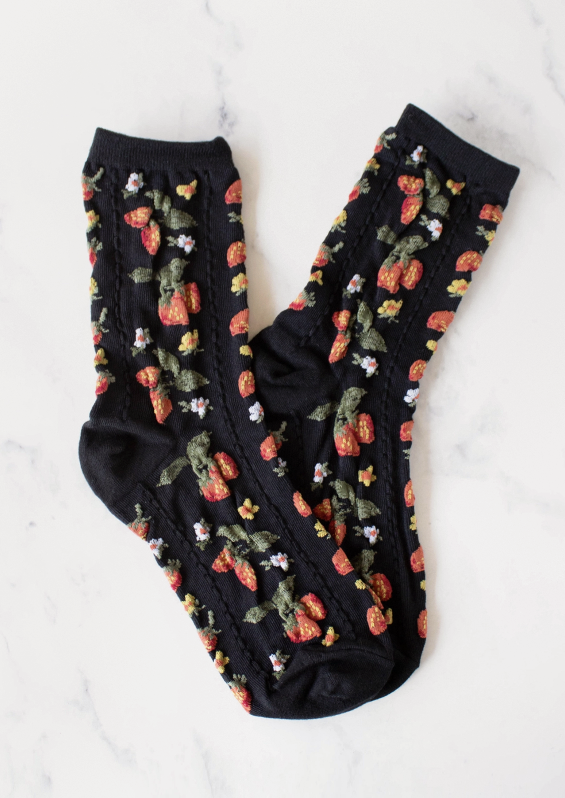 A pair of black socks with red, white and yellow strawberry pattern.
