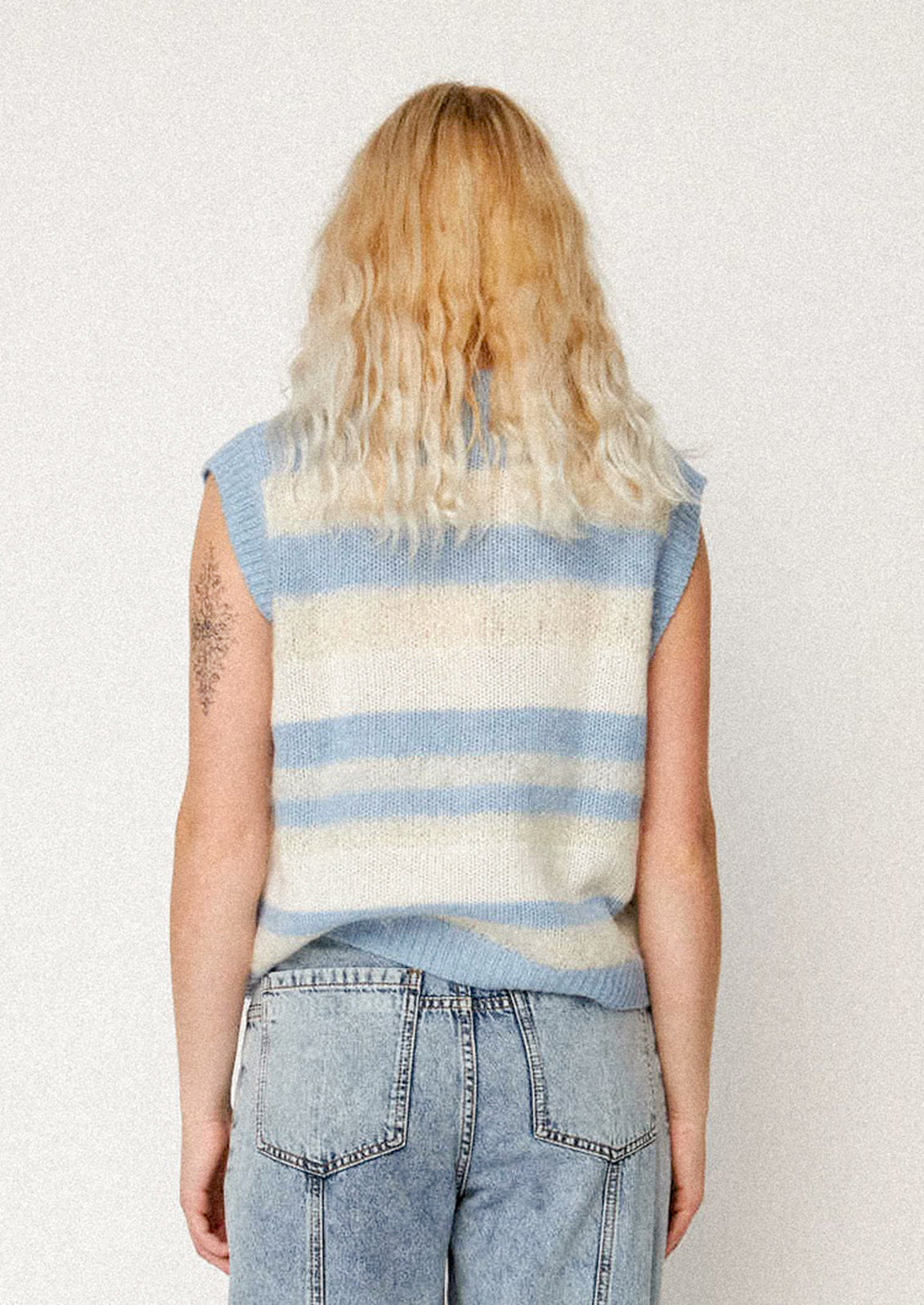 A woman wearing a striped blue and cream sweater vest.