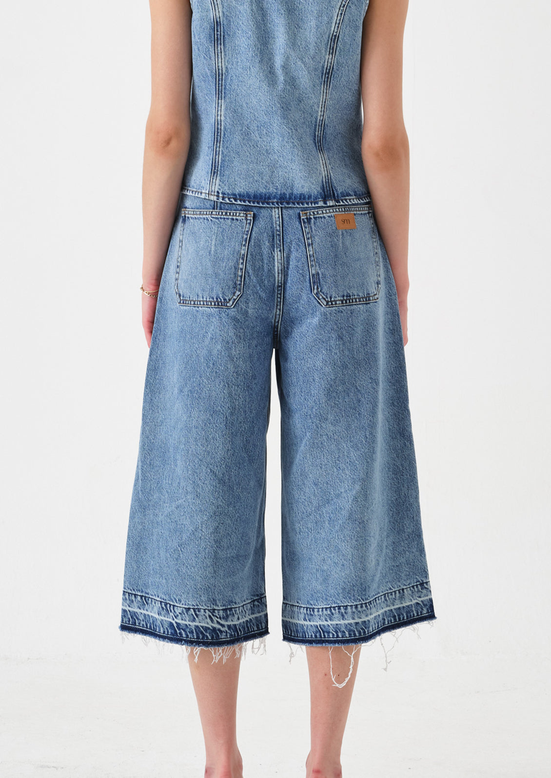 A person wearing a pair of denim culotte pants.