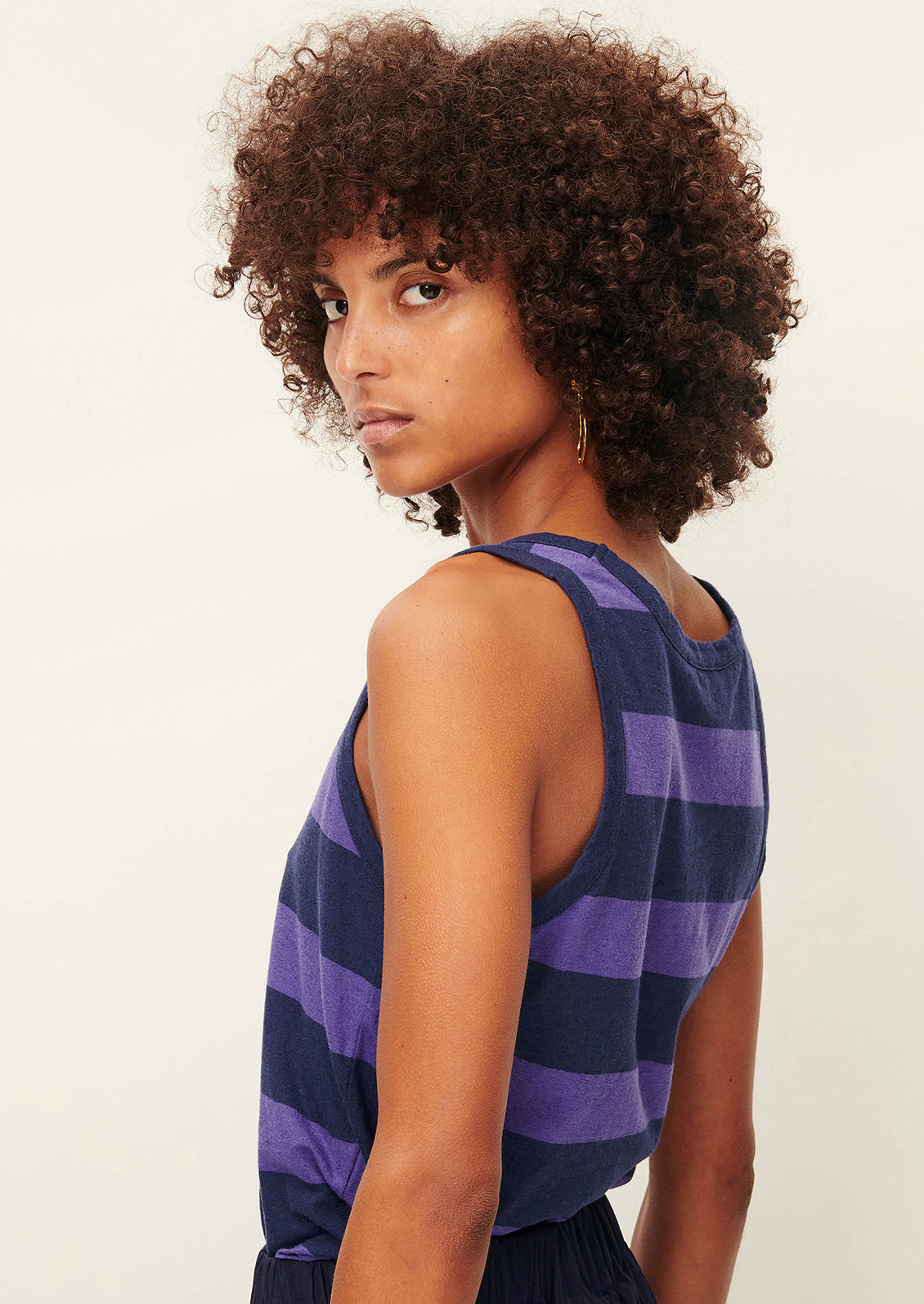 A woman wearing a scoop neck tank top in blue and purple stripes.