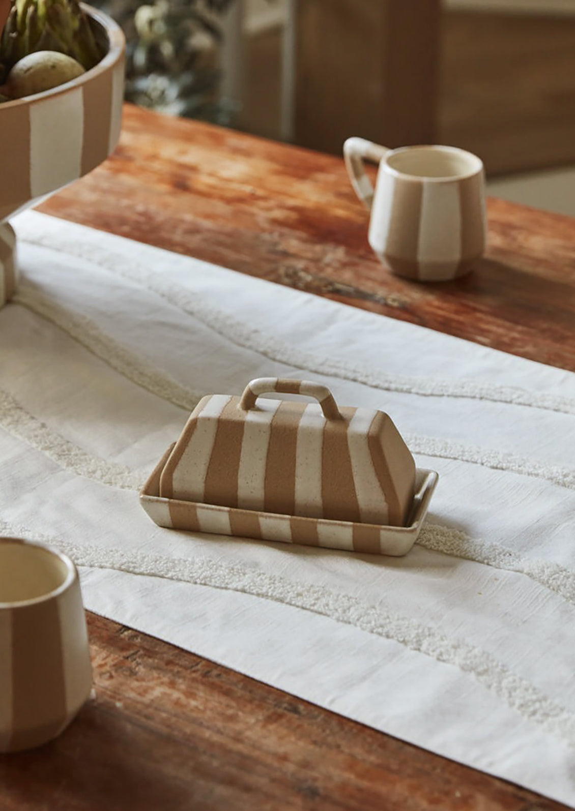 A rectangular, modern looking ceramic butter dish with white and sand stripe pattern.