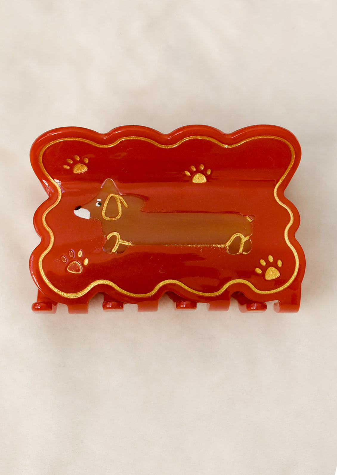 A red hair claw with scalloped shape and dachshund motif.