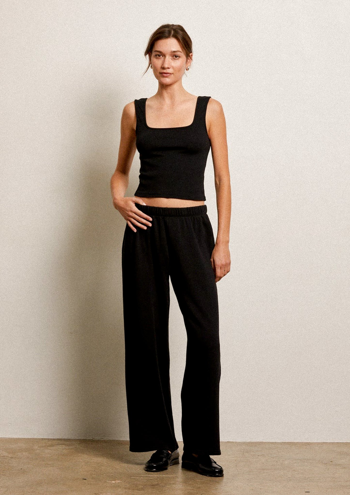 Woman wearing a black sleeveless top and black wide-leg pants.
