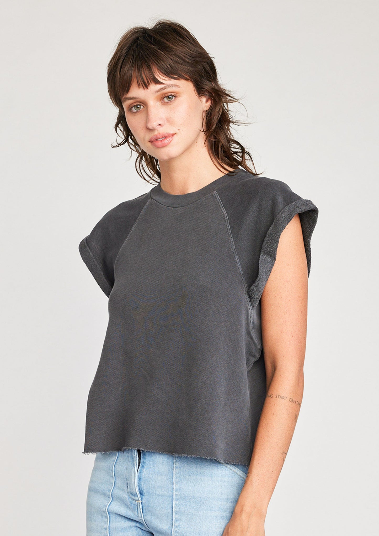 A woman wearing a raglan short sleeve sweatshirt in dark grey.
