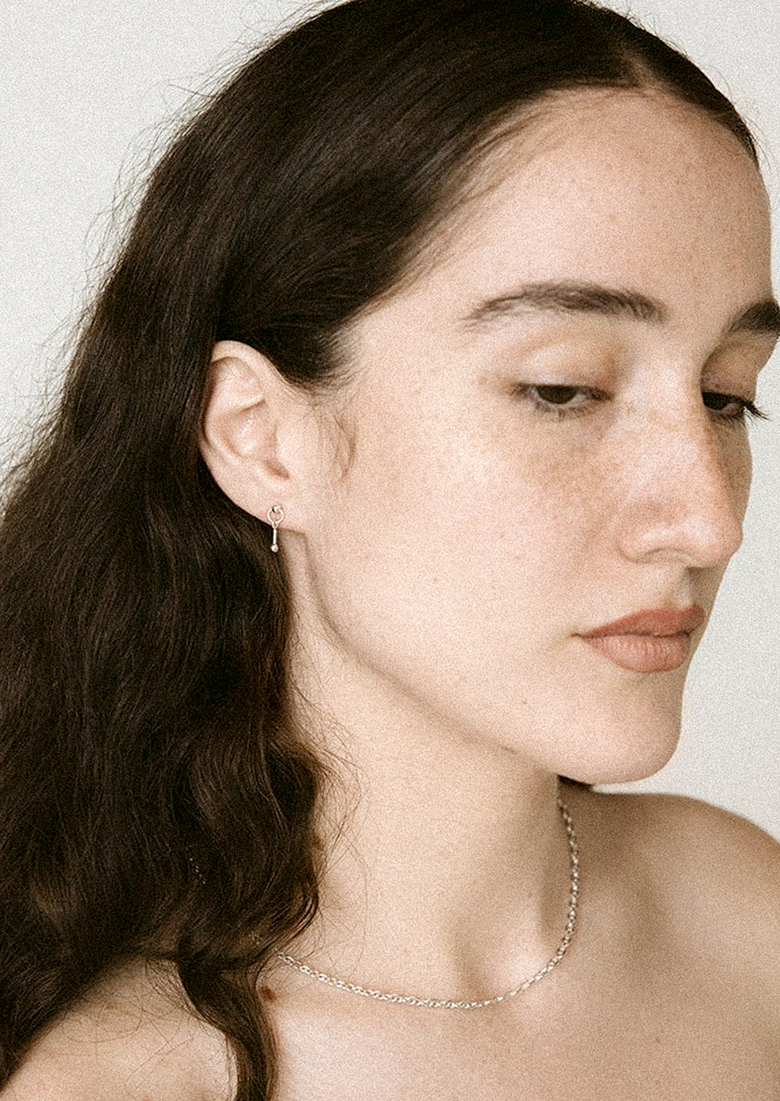 A pair of sterling silver stud earrings in dangling barbell shape.