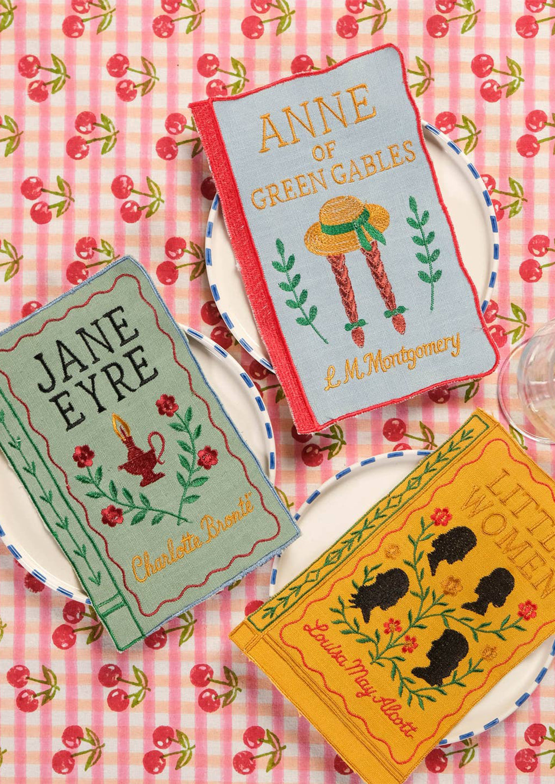 Four napkins resembling book covers of 'Wuthering Heights', 'Jane Eyre', 'Anne of Green Gables', and 'Little Women'.
