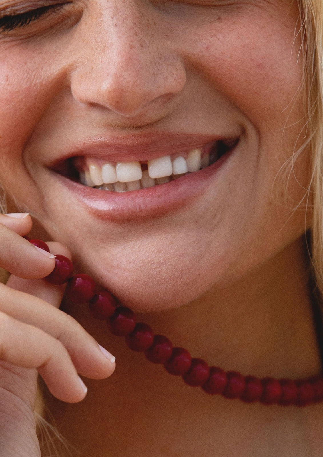 Close-up of a woman's face with a red beaded necklace