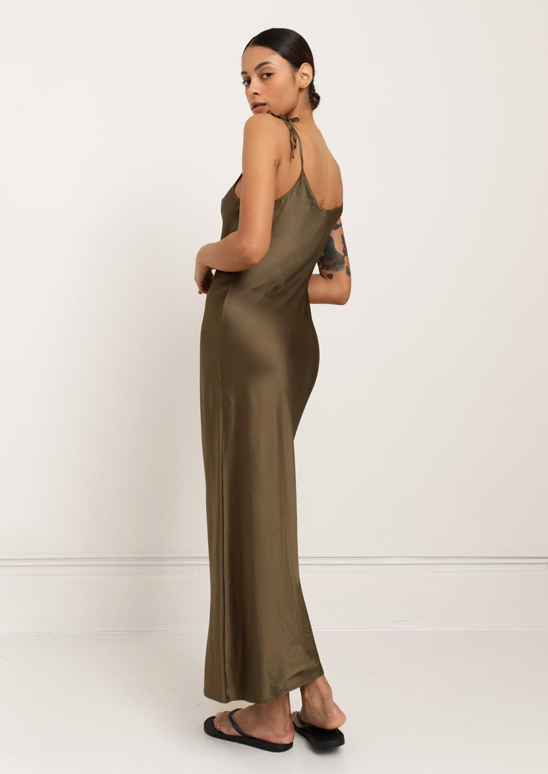 A person wearing a long slinky tank dress in olive green.
