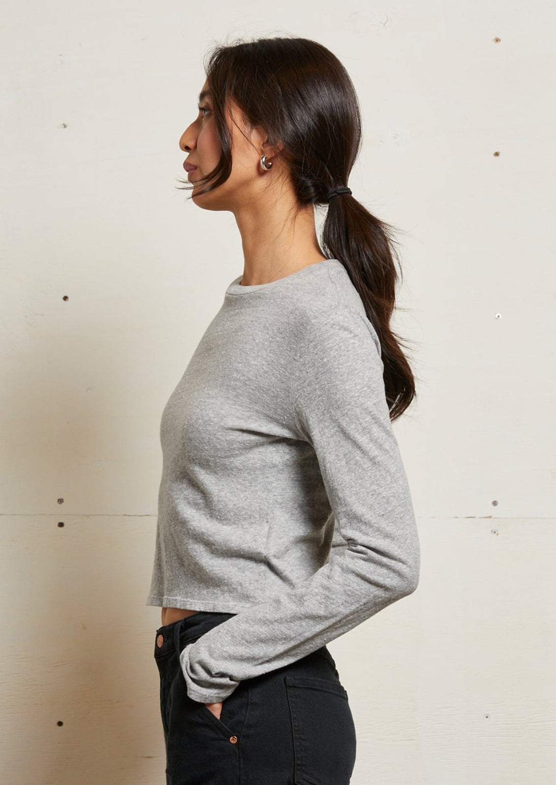 A woman wearing a long sleeve heathered grey tshirt.