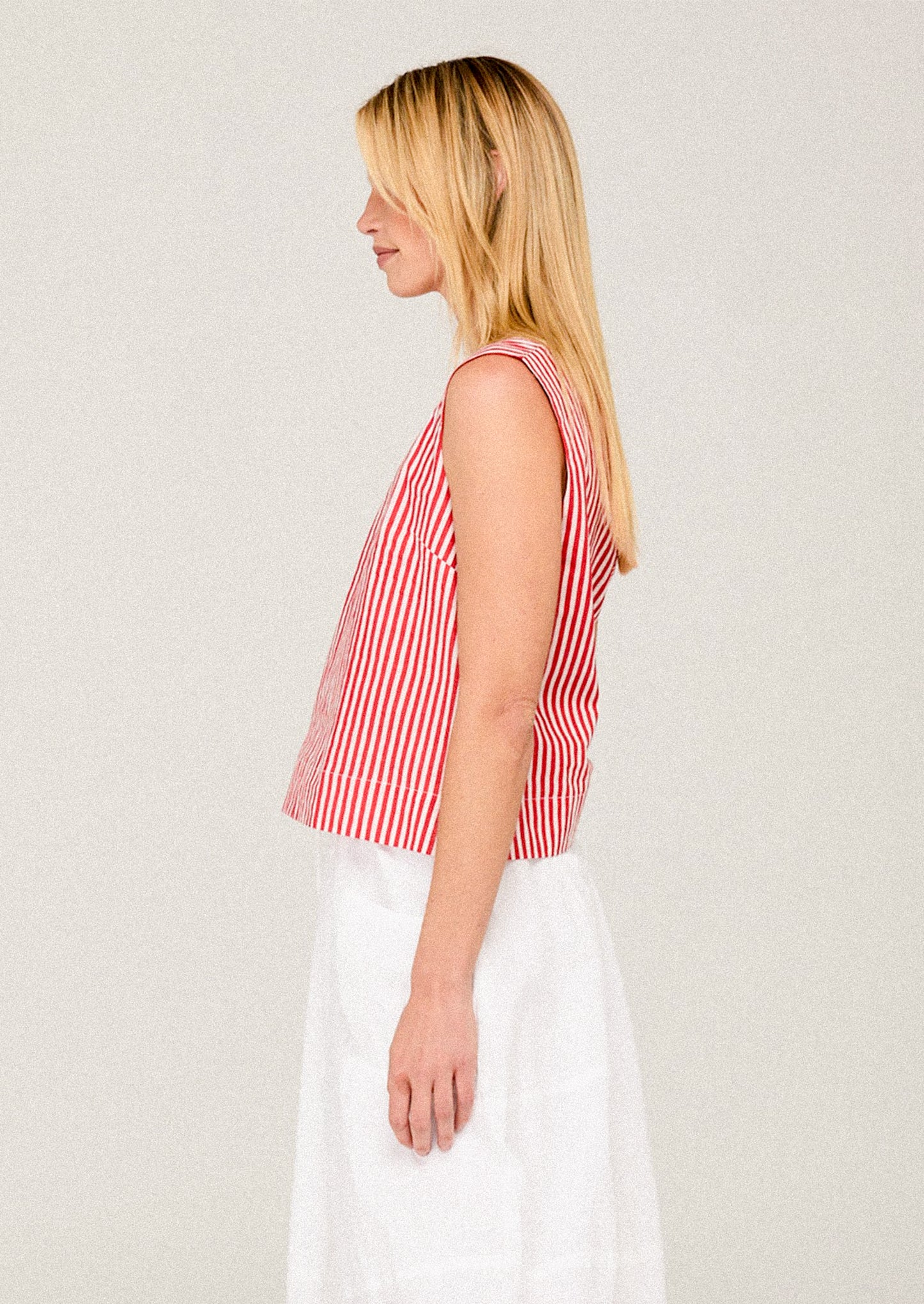 Woman wearing a red and white striped sleeveless top against a plain background