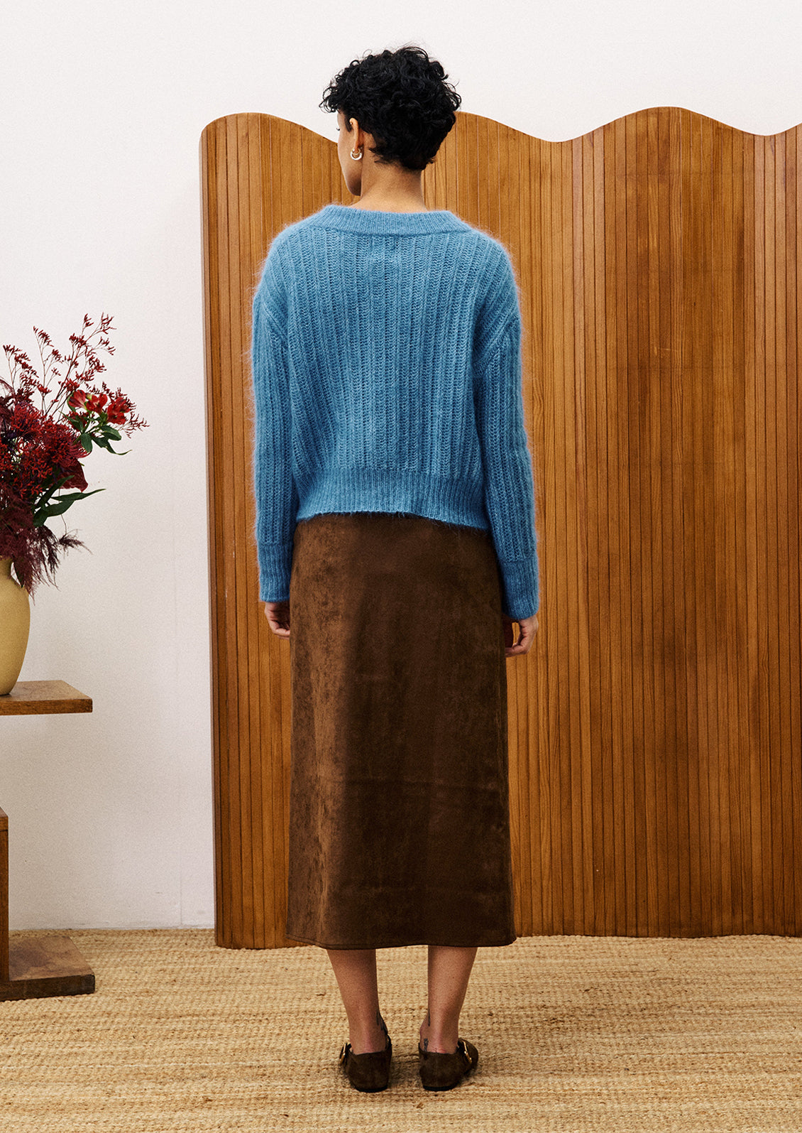 A woman wearing a dusty blue v-neck sweater.