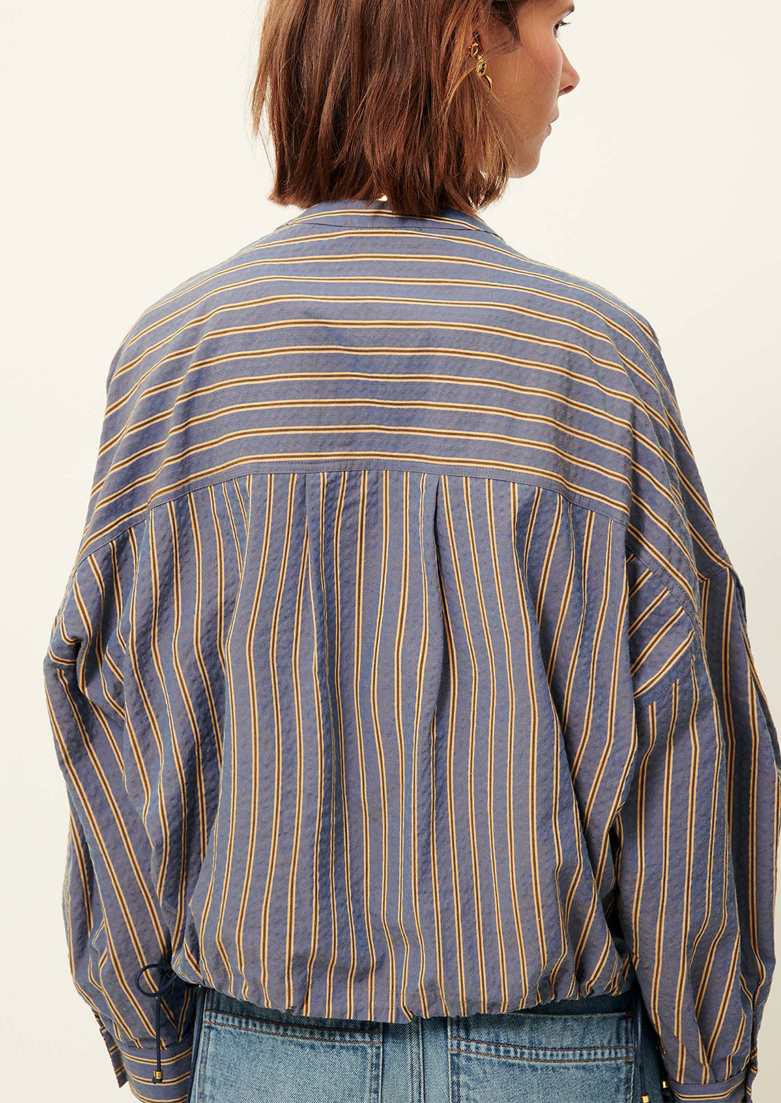Person wearing a blue and yellow striped shirt with a neutral background