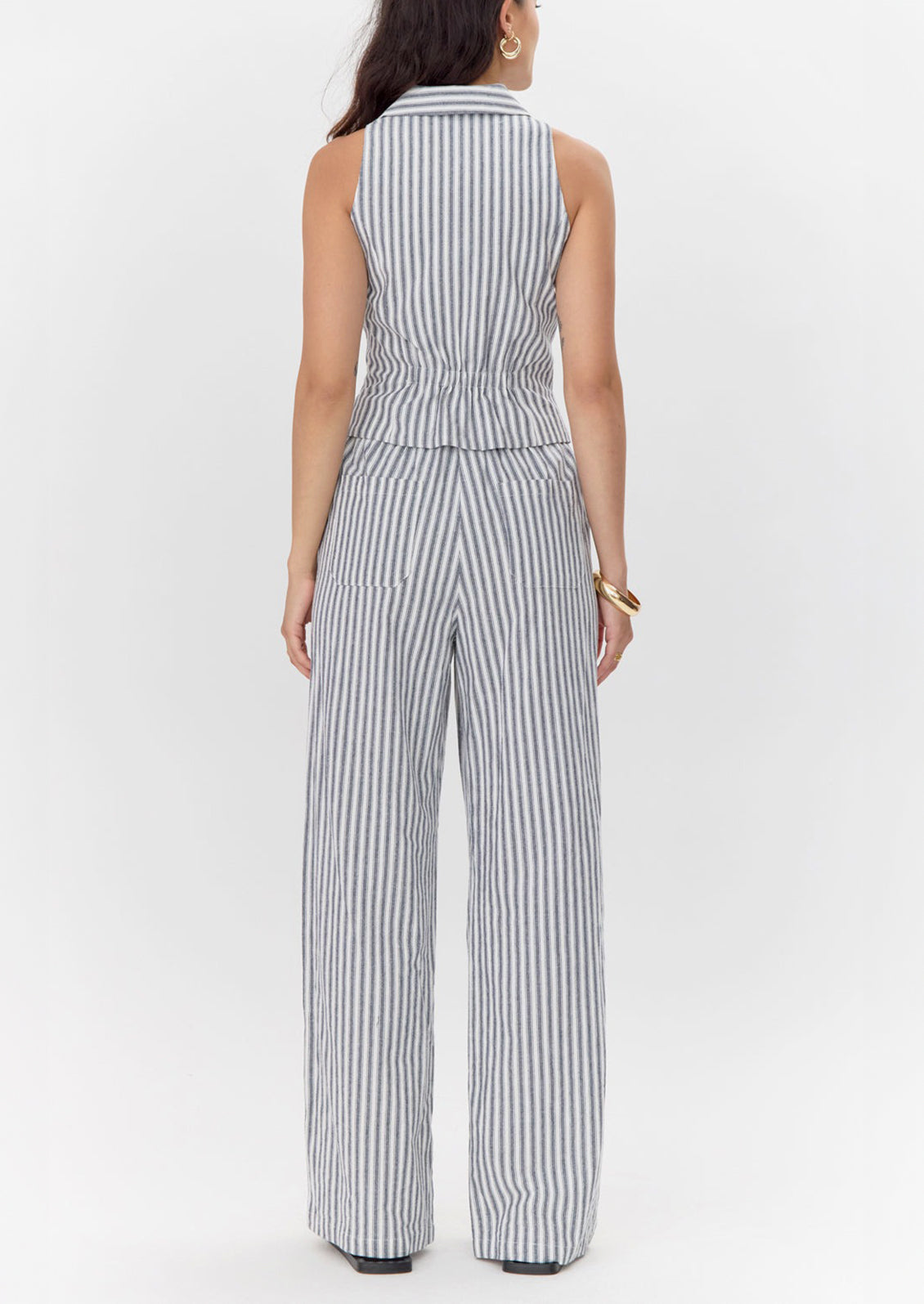 Woman wearing a sleeveless striped jumpsuit on a white background