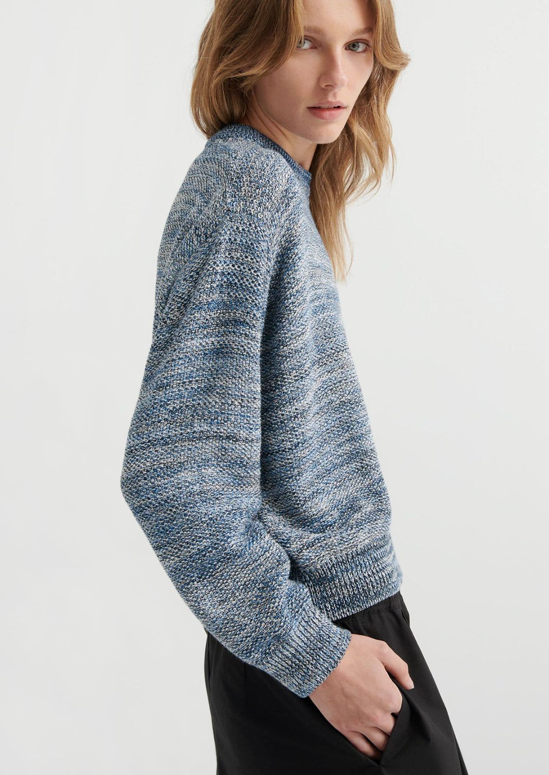 Woman wearing a blue knitted sweater on a white background