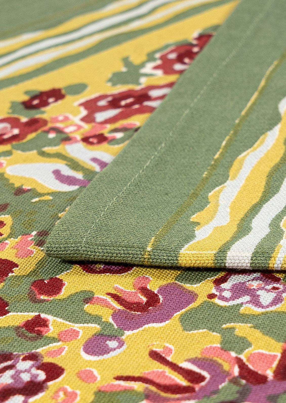 A floral patterned table runner in green with red, yellow, white and purple pattern.
