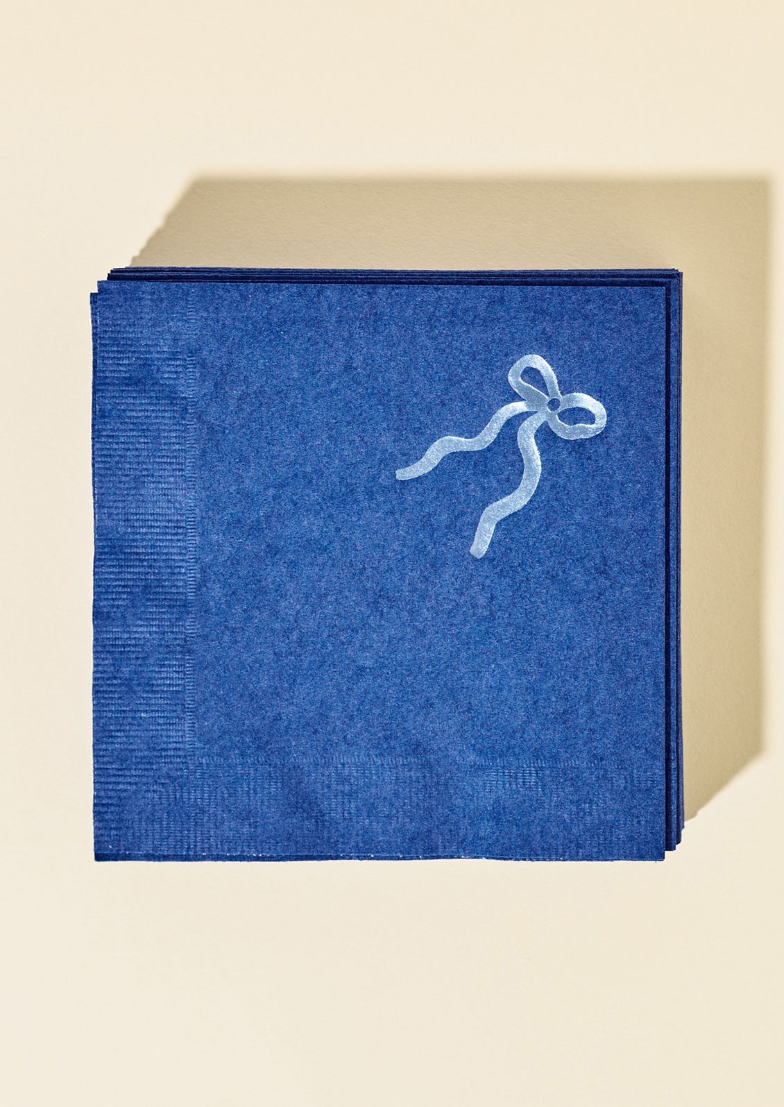 Blue paper napkins with blue foil bow graphic at corner.