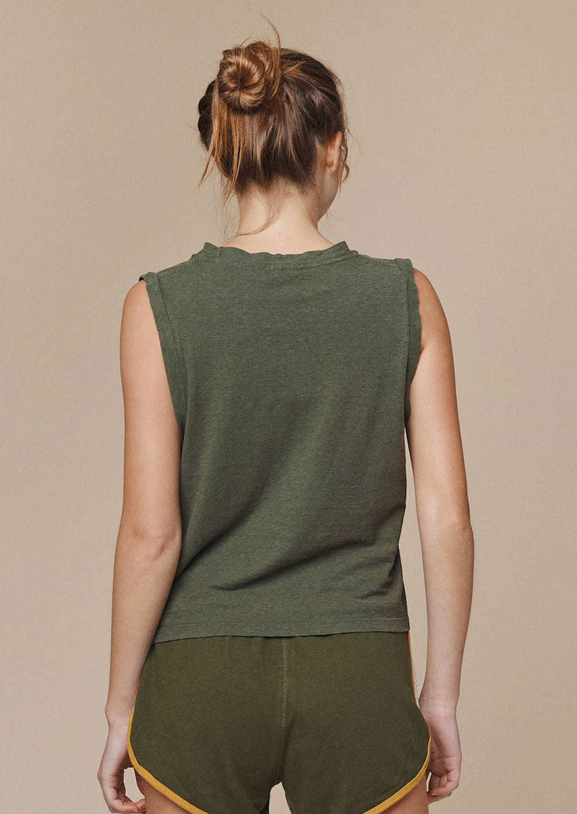 A person wearing a muscle tee in olive green.